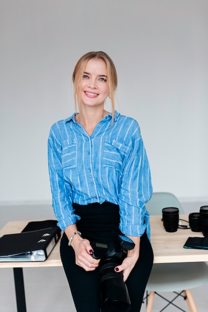 Free photo smiley young woman holding a camera