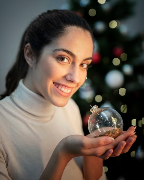 Foto gratuita globo di natale della holding della giovane donna di smiley