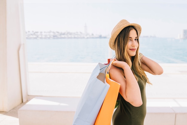 Foto gratuita smiley giovane donna in posa con borse della spesa e cappello