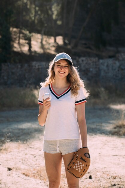 Smiling active female with baseball and glove outdoors