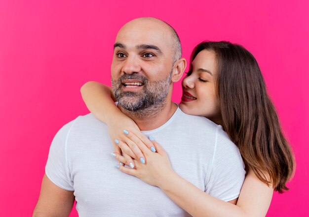 Smiling adult couple man looking at side woman putting hand on his shoulder keeping hands together looking at him 