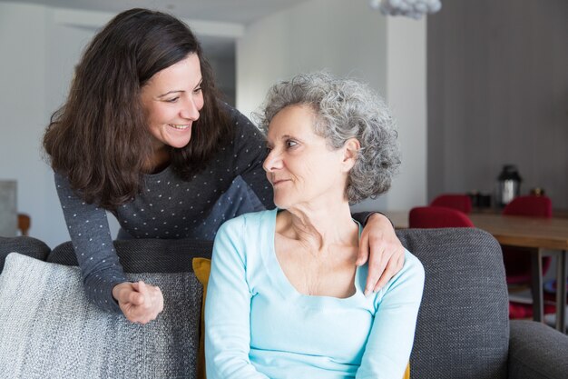 Smiling adult daughter supporting sad senior mother