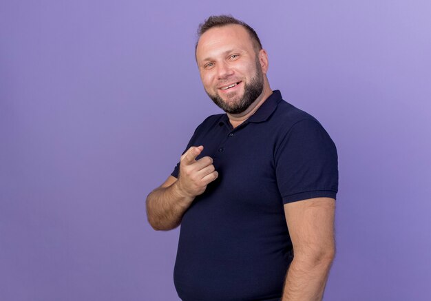 Smiling adult slavic man standing in profile view and pointing isolated