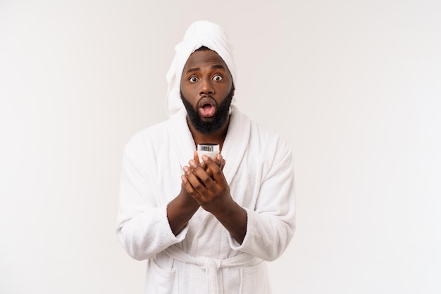 Smiling African American man applying cream on his face Man's skin care concept