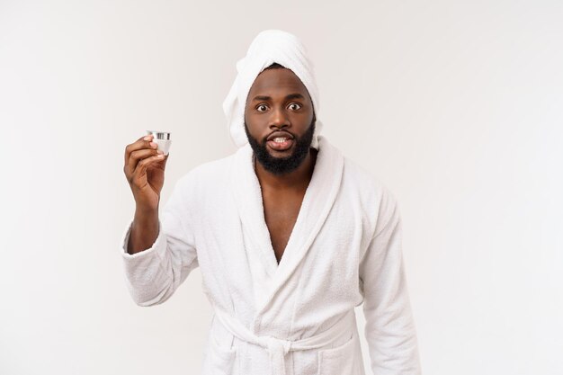 Smiling African American man applying cream on his face Man's skin care concept