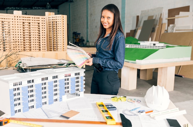 Smiling African American woman showing examples of colours near table with equipments