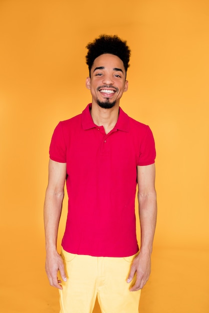 Улыбающийся афро-американский молодой человек улыбается уверенно в яркой летней одежде.