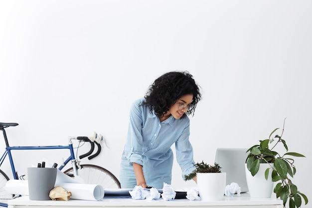 Free photo smiling african american young woman engineer using laptop at office