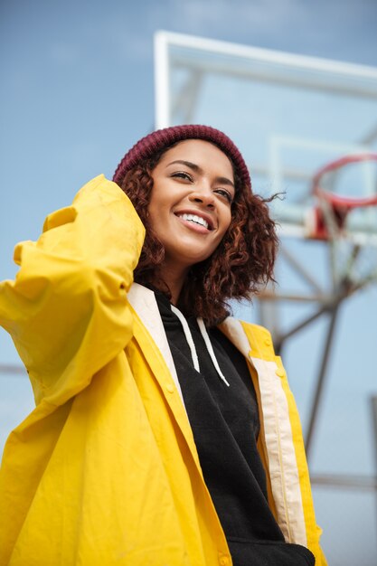 Smiling african curly young lady wearing yellow coat