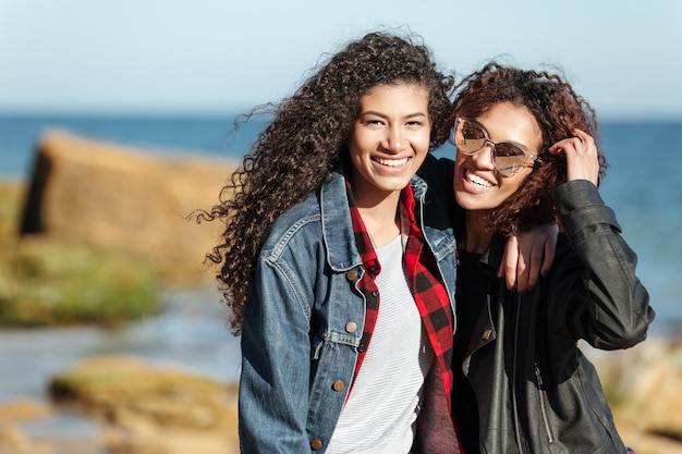 Smiling african woman friends walking outdoors at beach.