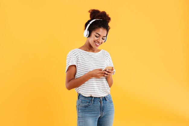 Smiling african woman listening music and using phone