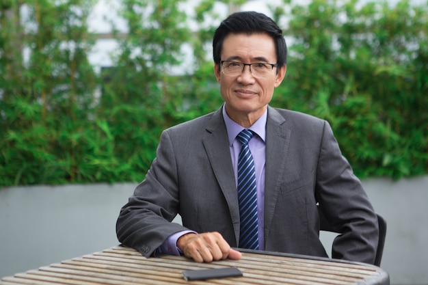 Smiling Aged Businessman Sitting in Cafe