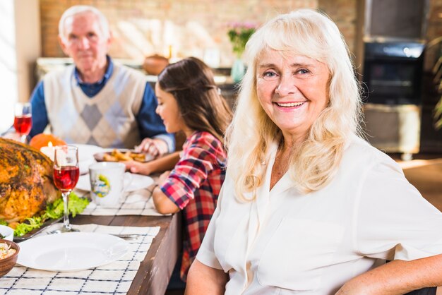 Smiling aged woman sitting at table 