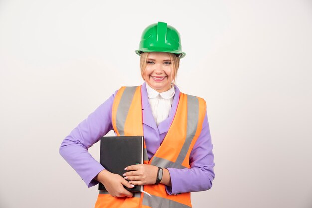 Smiling architect woman in helmet holding tablet on white.