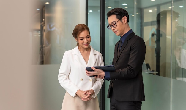 Улыбающаяся азиатская деловая женщина показывает документ своему менеджеру во время встречи в офисе
