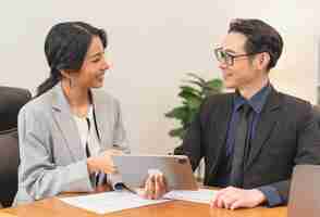 Free photo smiling asian businesswoman showing tablet to her manager during a meeting in the office