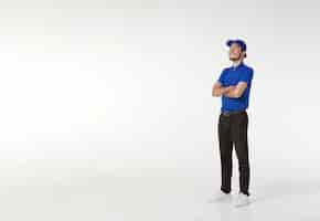 Free photo smiling asian delivery man in blue uniform standing with arms crossed