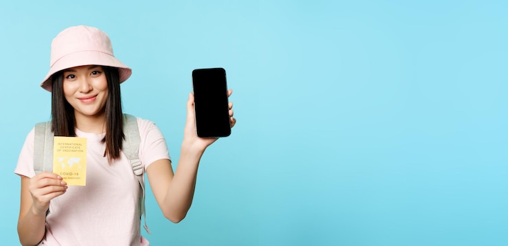 Free Photo smiling asian girl shows international covid vaccination certificate health passport on smartphone s