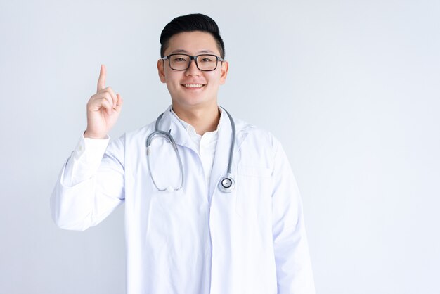 Улыбаясь азиатских мужской доктор, указывая вверх