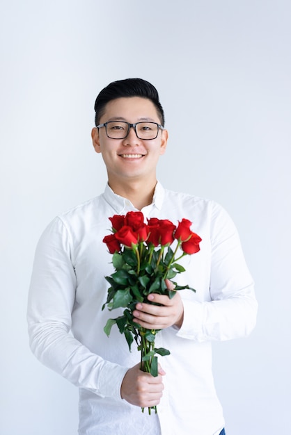 Smiling Asian man holding bunch of roses