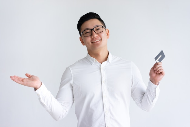 Smiling Asian man holding credit card and throwing up hand