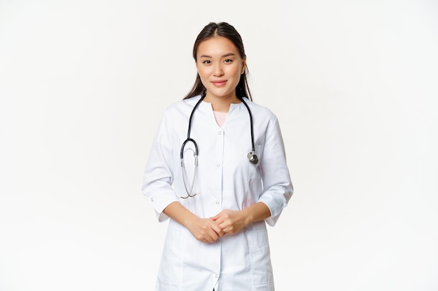 Free photo smiling asian medical worker with stethoscope wearing doctor uniform looking helpful at patient stan...