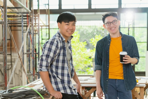 若いインテリアdreativeデザイナーの肖像画の笑顔のアジアのチームワークは、建設家のリフォームの背景を持つ自信を持ってスマートなチームを一緒に立っています