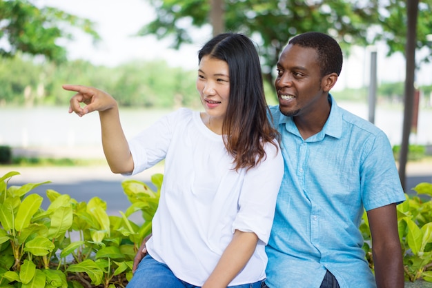 Smiling Asian woman showing direction to African American man. 