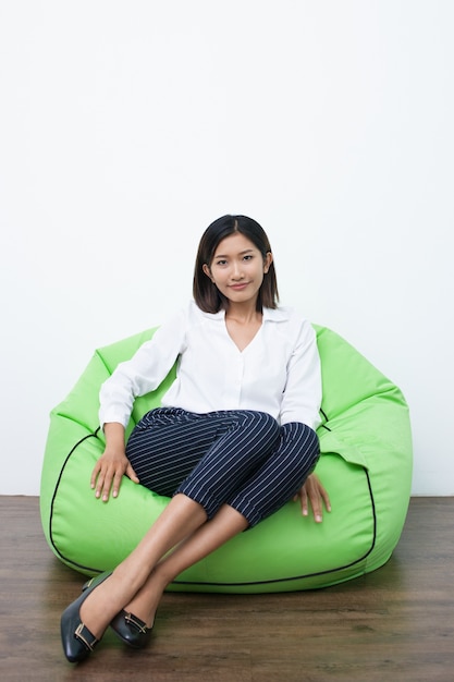 Free photo smiling asian woman sitting on beanbag