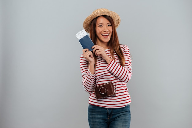 Smiling asian woman in sweater and hat with retro camera