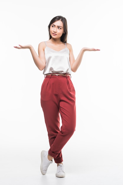 Smiling asian woman with open palms showing copy space for product isolated on white wall.