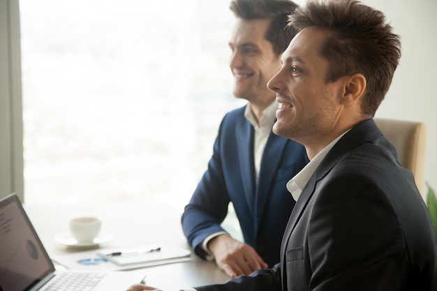 Smiling attentive businessmen attending conference meeting, side