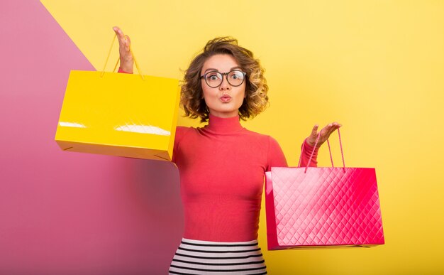 Smiling attractive excited woman in stylish colorful outfit holding shopping bags