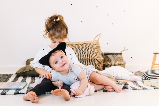 Free photo smiling baby on legs of girl