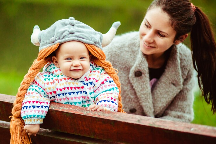 Free Photo smiling baby and mother sitting on bench