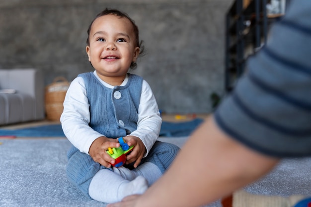 Bambino sorridente che gioca con il giocattolo e sua madre