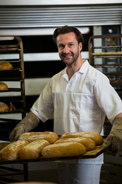 Smiling baker carrying a tray of baked buns