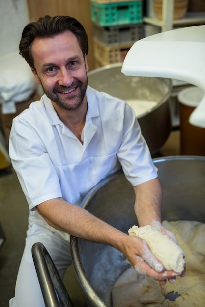 Smiling baker preparing dough