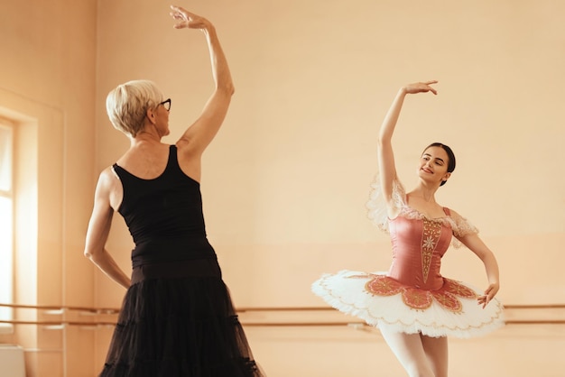 Бесплатное фото Улыбающаяся балерина и ее инструктор репетируют в балетной студии