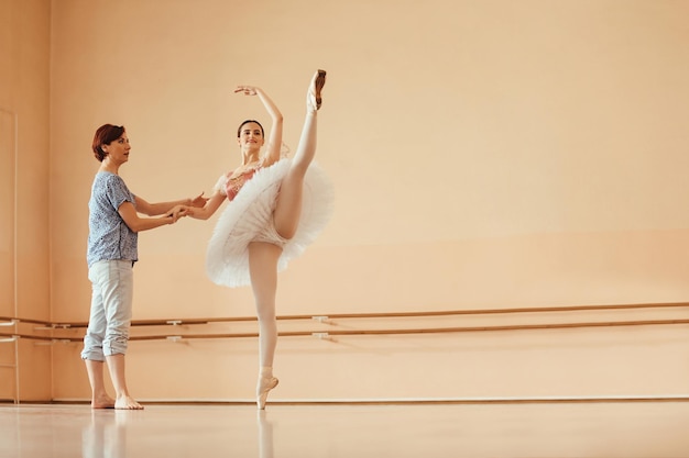 Smiling ballerina dancing with help of female instructor on ballet class in a studio Copy space