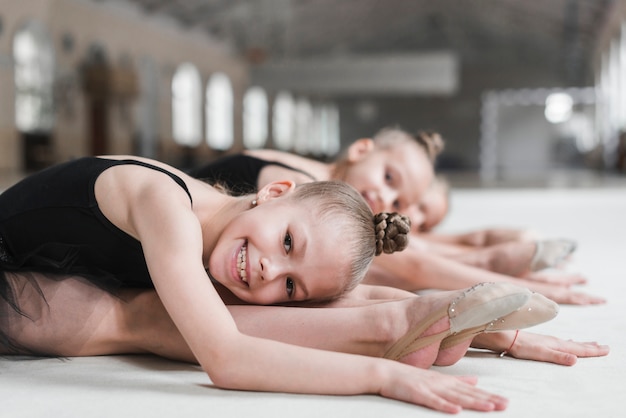 Smiling ballerina girl posing on dance floor with her friend
