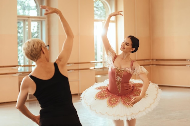 ダンススタジオで彼女のバレエ教師とリハーサルをしている笑顔のバレリーナ