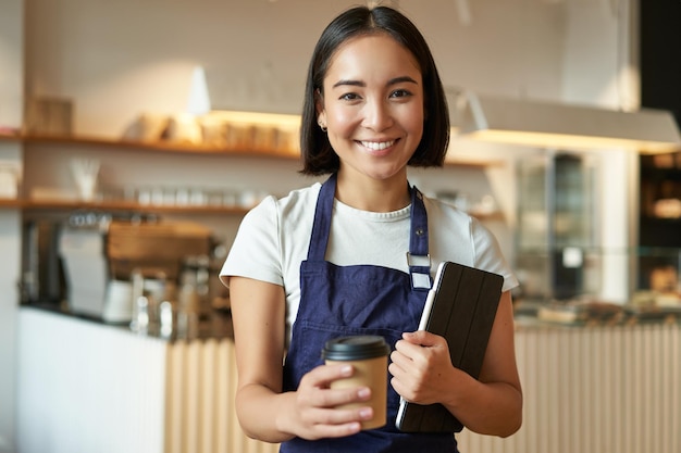 Free photo smiling barista cafe waitress giving out takeaway coffee order prepared cappuccino for takeout