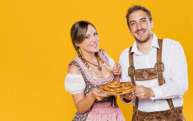 Foto gratuita coppie bavaresi sorridenti con le ciambelline salate