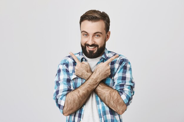 Smiling bearded guy demonstrating products, pointing sideways