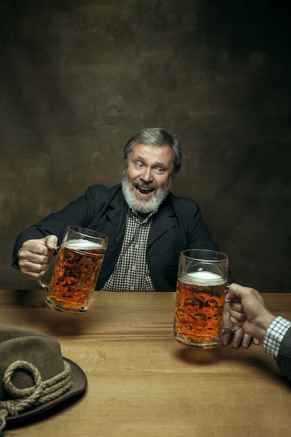 Smiling bearded male drinking beer in pub