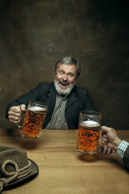 Smiling bearded male drinking beer in pub