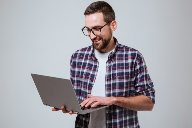 Smiling Bearded man in eyeglases using laptop
