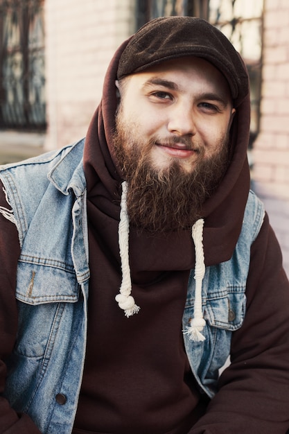 Foto gratuita sorridente uomo barbuto che indossa un giubbotto di jeans