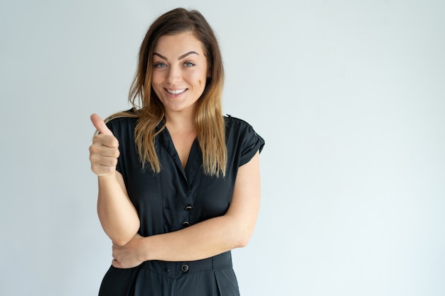 Smiling beautiful brown-haired woman showing thumb up. Lady looking at camera.